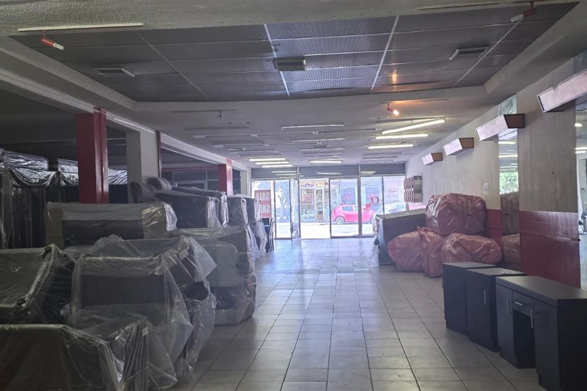 Spacious commercial open-plan retail area featuring tiled flooring, suspended ceilings, and a glass storefront entrance, suitable for various business applications.