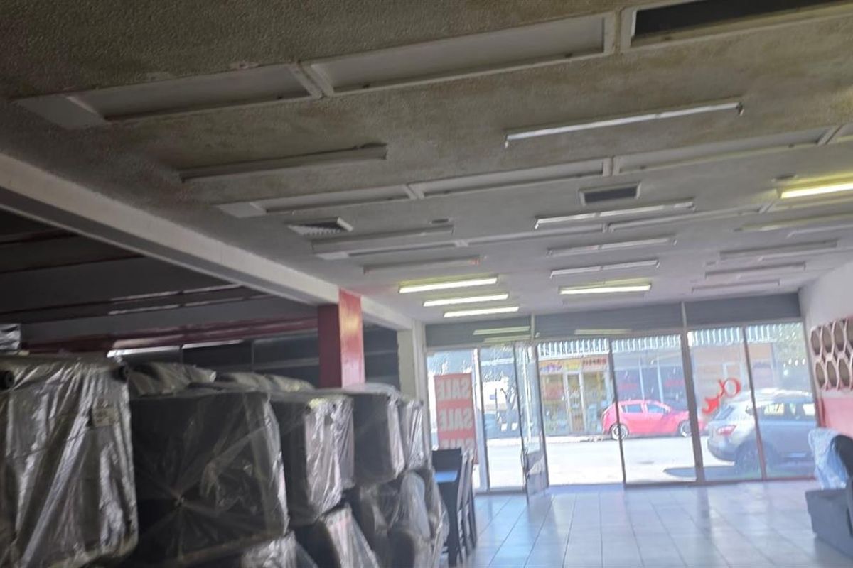 Open plan commercial retail space featuring tiled flooring, extensive glass storefront frontage, and integrated fluorescent lighting throughout the ceiling.