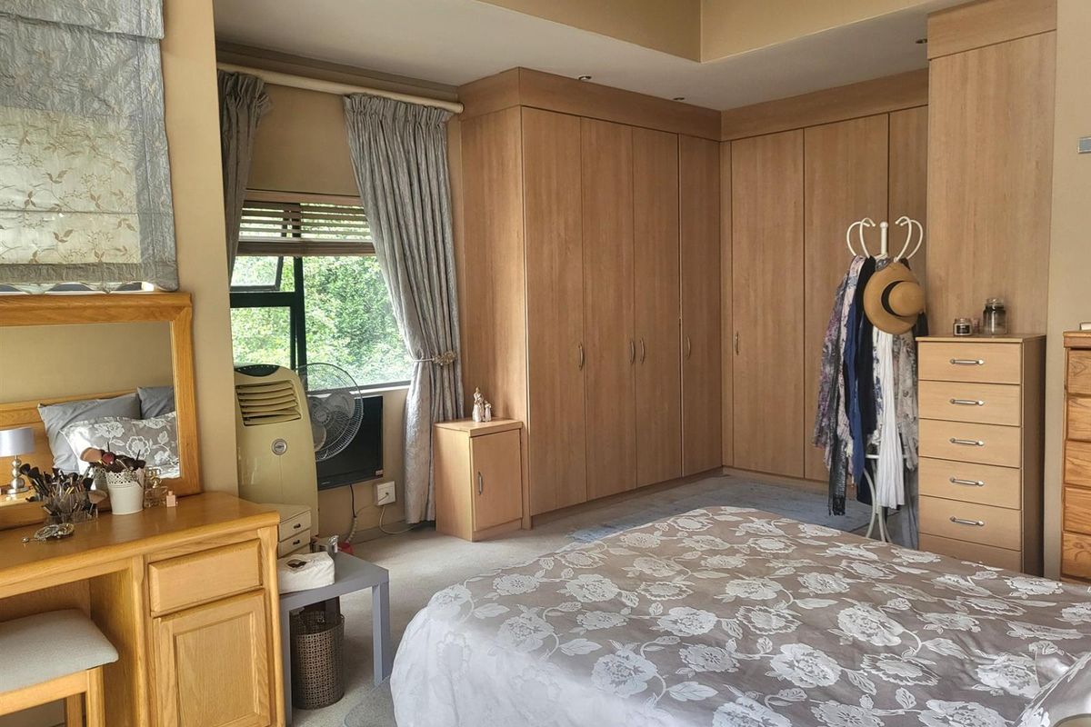 A bedroom featuring extensive built-in wooden cabinetry and wardrobes, providing ample storage space with a neutral color palette.