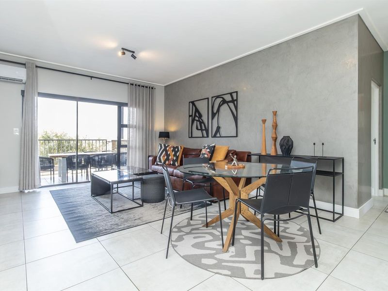Spacious open-plan living and dining area featuring modern tiled floors, a textured feature wall, and large sliding doors leading to a private balcony.