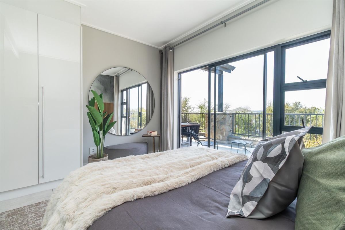 Modern bedroom featuring a built-in wardrobe and large sliding glass doors providing direct access to a private balcony with scenic views.