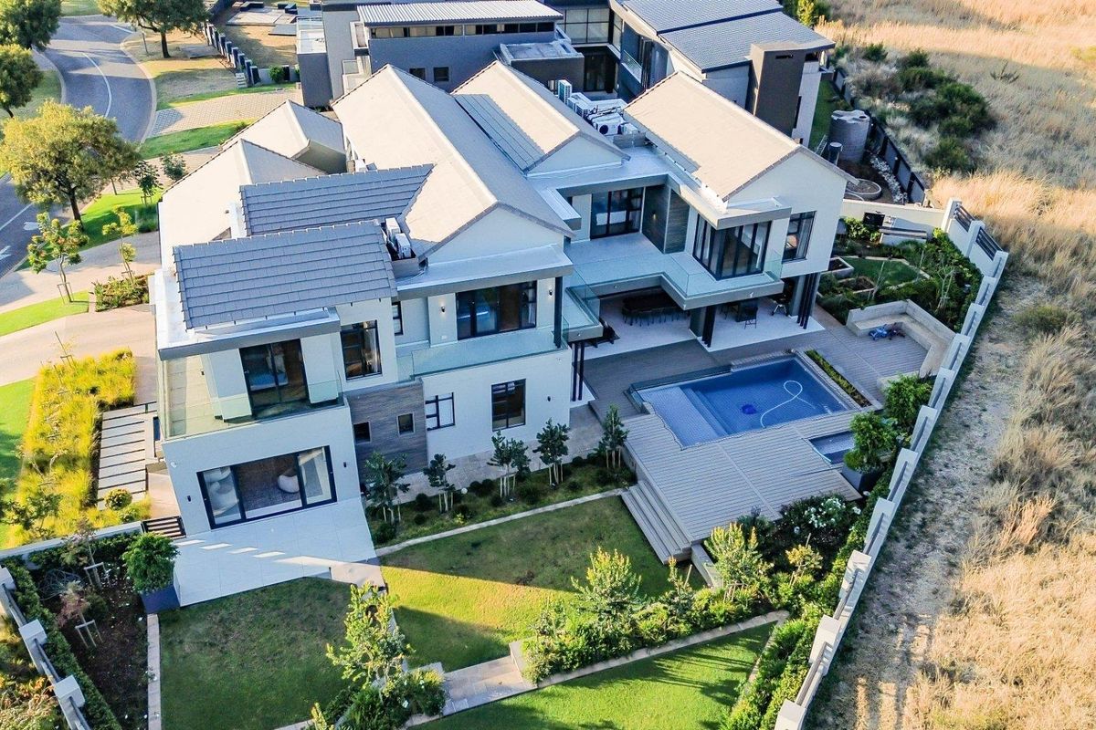Aerial view of a modern luxury residence featuring a swimming pool, landscaped garden, multi-level patio areas, and contemporary architectural design.