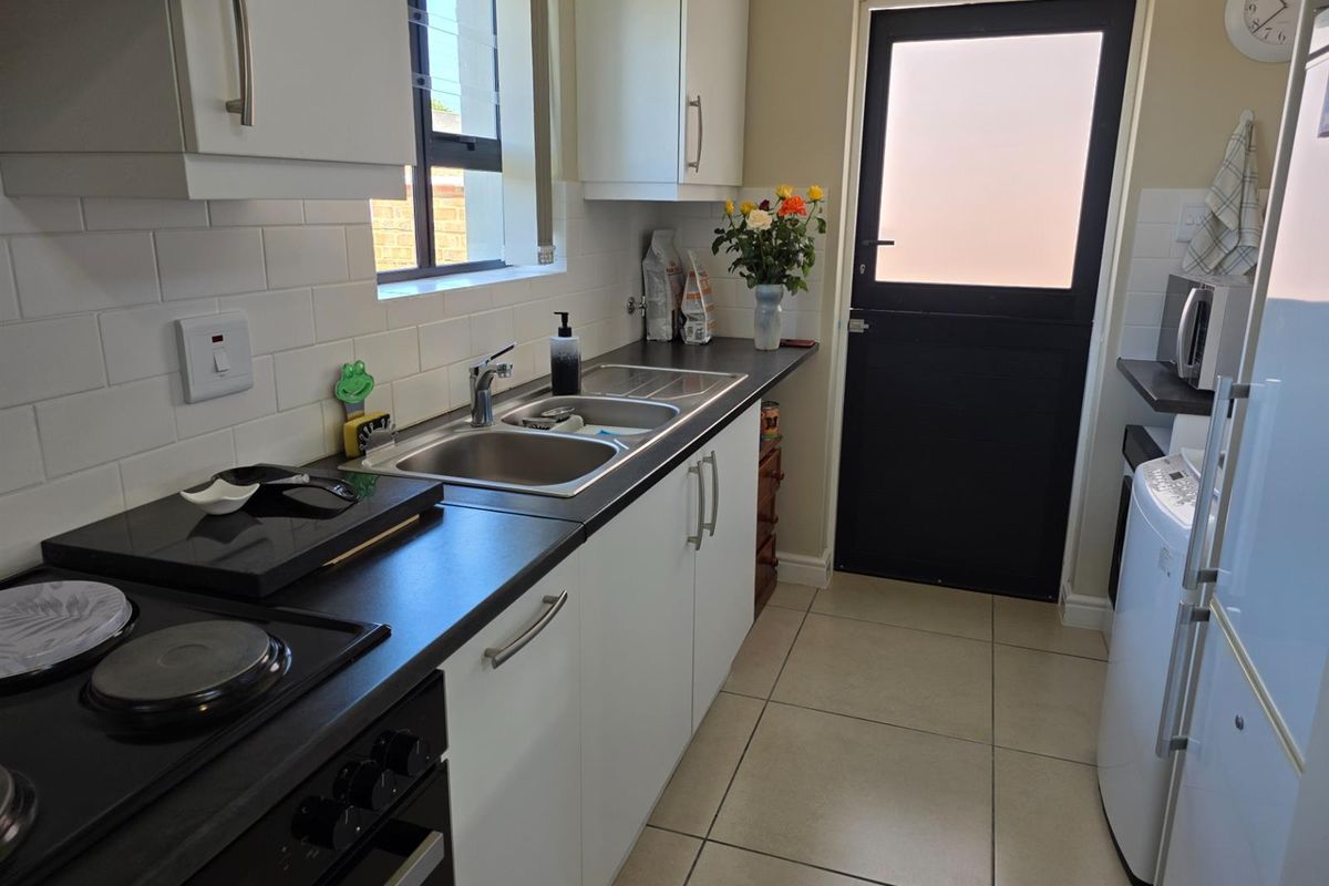 A clean, functional kitchen featuring white cabinetry, dark countertops, subway tile backsplash, and a stable door leading to the exterior.