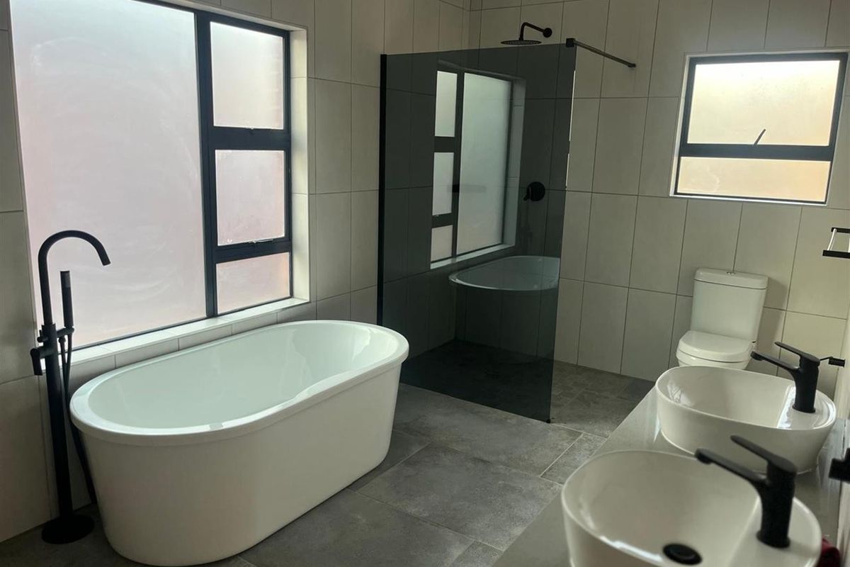 Modern bathroom featuring a freestanding bathtub, glass-enclosed walk-in shower, dual vessel sinks, and contemporary matte black fixtures throughout.