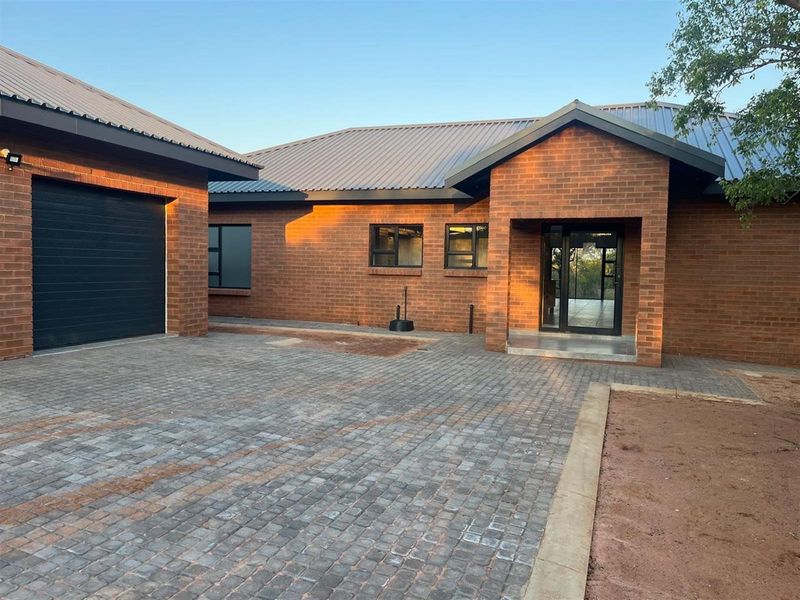 Front exterior view of a modern face-brick house featuring a paved driveway, single garage, and a covered entrance porch.