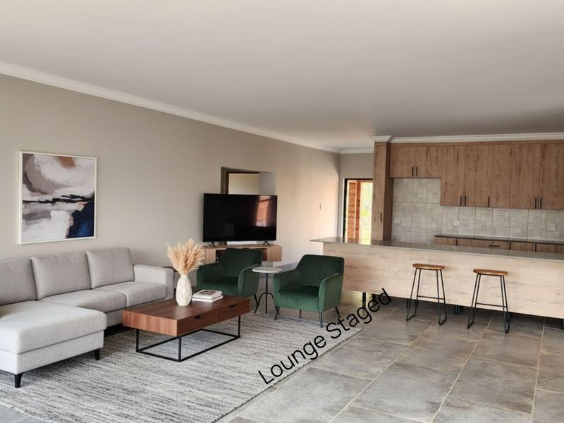 An open-plan living area featuring a modern kitchen with wood-finish cabinetry, a breakfast bar, and tiled flooring throughout the combined space.