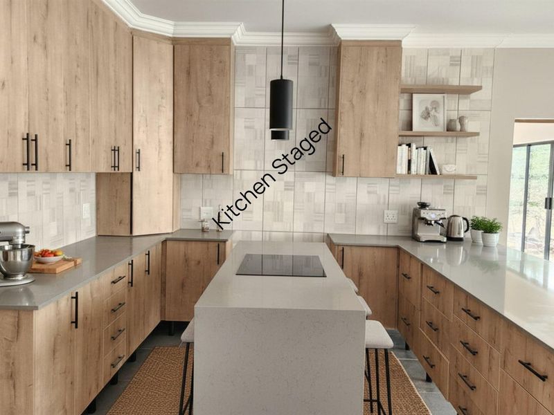 Modern kitchen featuring light wood cabinetry, stone countertops, a central island with an integrated cooktop, and stylish tiled backsplash.