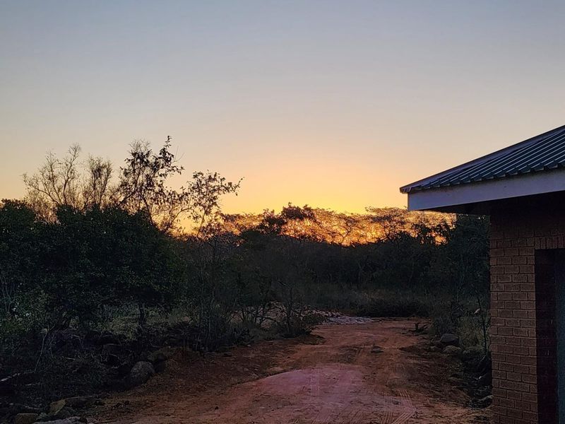 A scenic view of the property exterior at sunset, featuring a brick building facade and natural landscape surroundings.