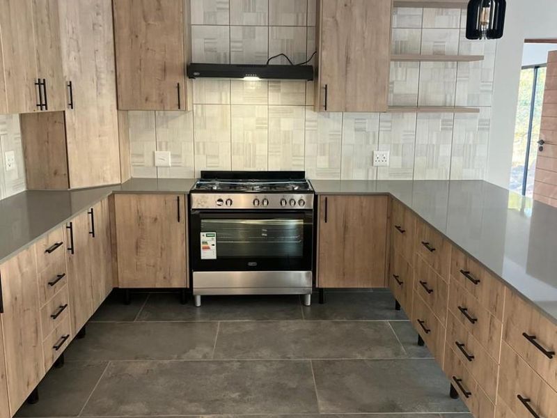 Modern U-shaped kitchen featuring wood-grain cabinetry, stone-look countertops, tiled backsplash, and a built-in gas stove with extractor fan.
