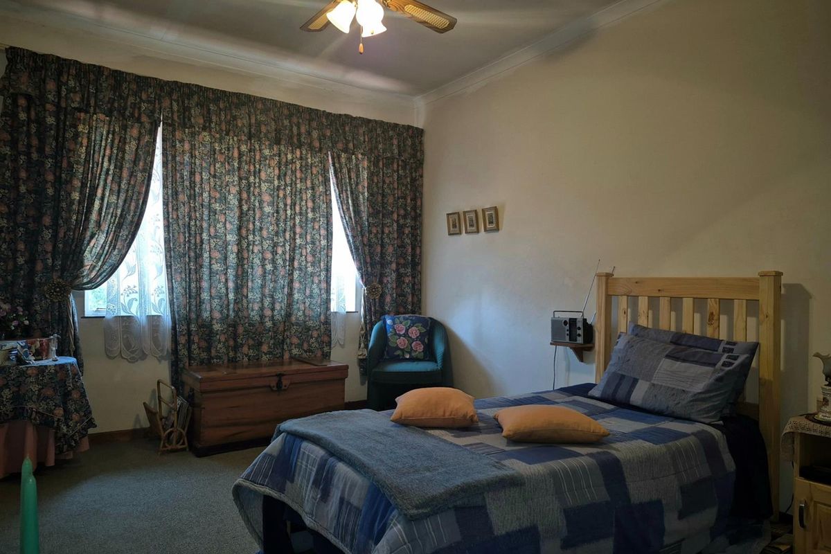 A bedroom featuring a ceiling fan and carpeted flooring, offering a functional space with natural light.