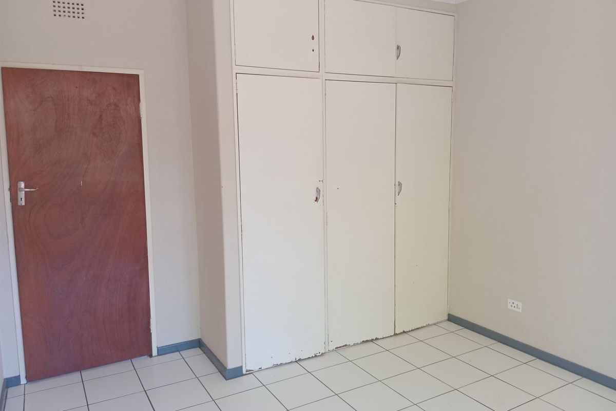 An empty bedroom featuring tiled flooring and built-in cupboards with overhead storage compartments.