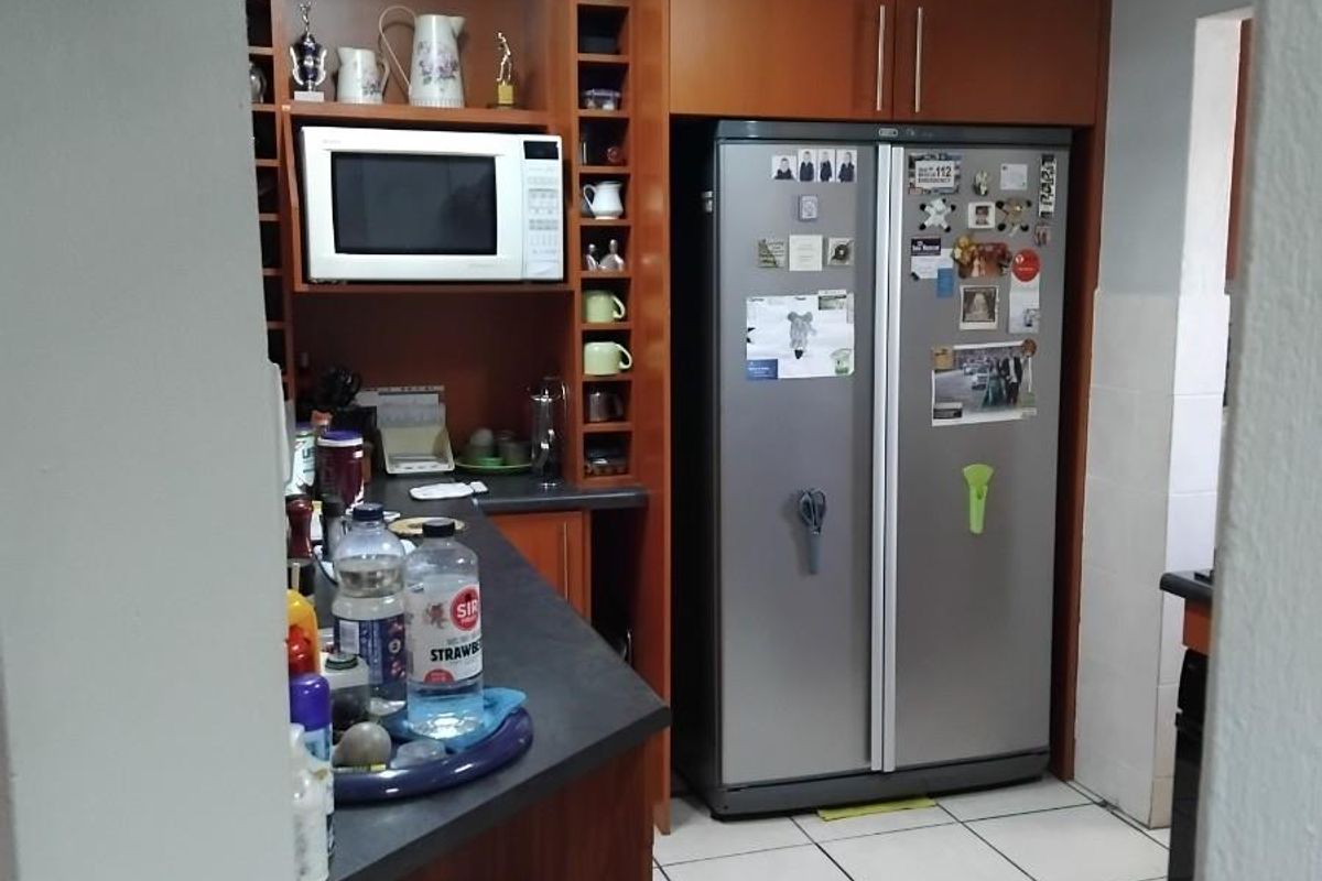 A functional kitchen featuring wooden cabinetry, built-in microwave housing, and tiled flooring, providing a practical layout for daily meal preparation.