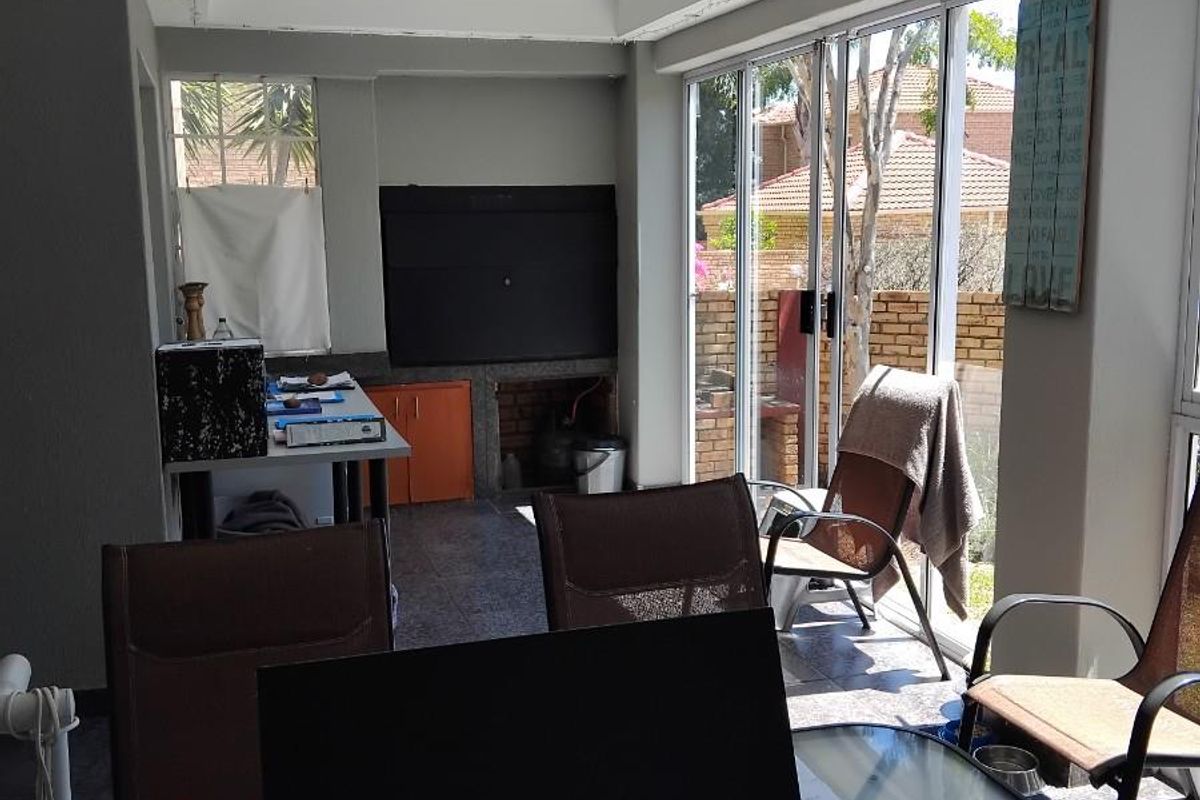 A multi-purpose living area featuring a built-in fireplace, tiled flooring, and large sliding glass doors providing access to the outdoor patio.