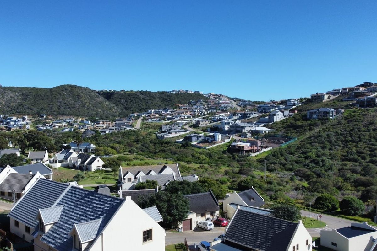 An elevated aerial view showcasing the surrounding residential estate landscape, hillside terrain, and established neighborhood housing.