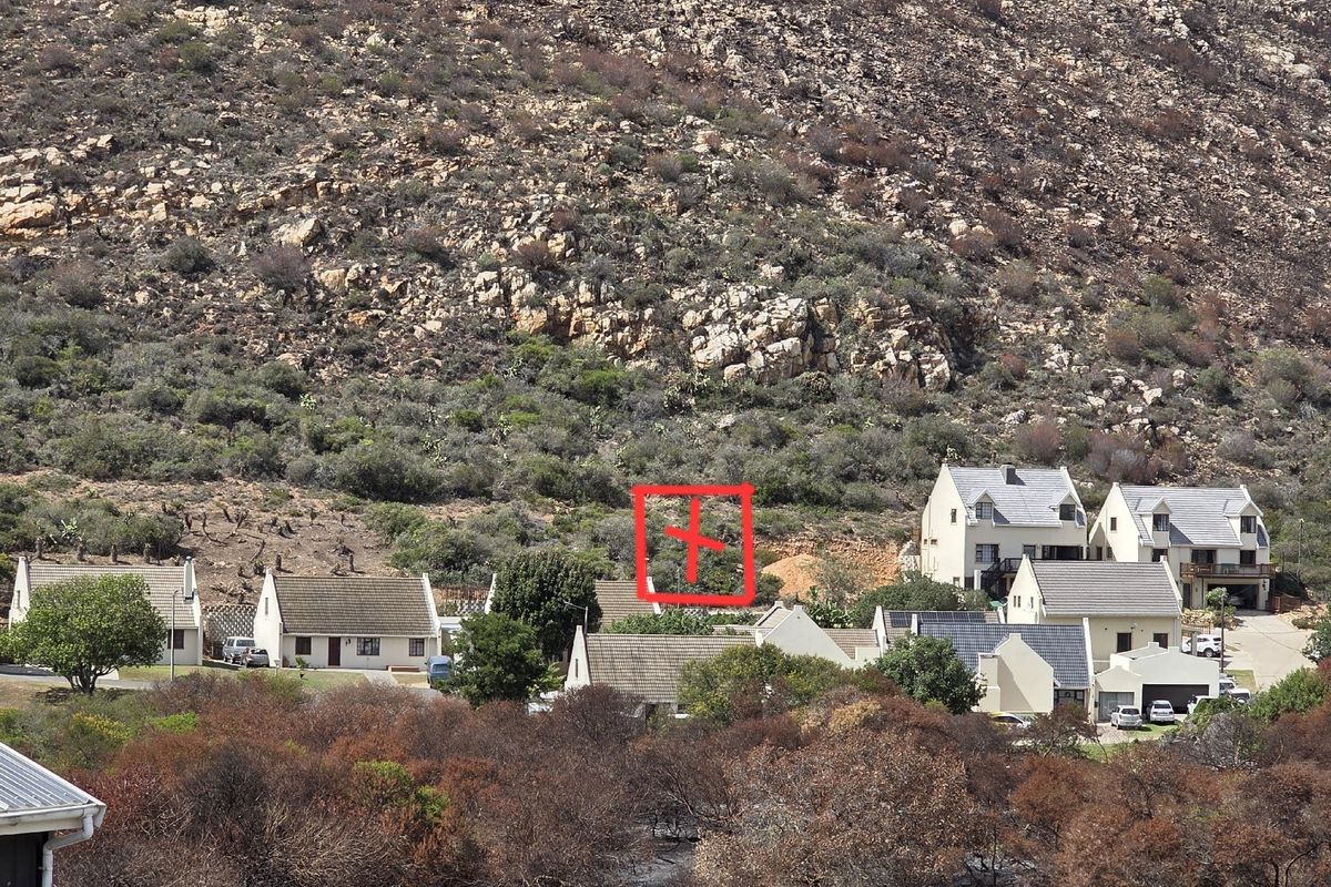 An elevated view of a residential development featuring vacant land plots nestled against a rocky hillside landscape.