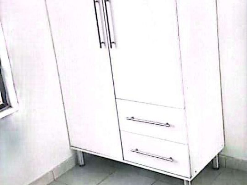 A bedroom space featuring tiled flooring and a freestanding wardrobe unit.