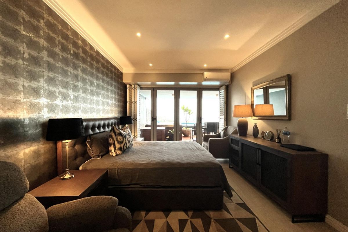 Spacious bedroom featuring recessed ceiling lighting, crown molding, and large glass sliding doors leading to a private balcony.