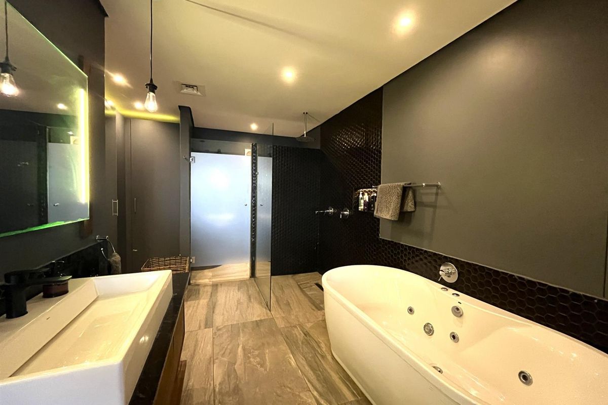 Modern bathroom featuring a freestanding jetted bathtub, a walk-in glass shower, and a contemporary vessel sink with integrated vanity lighting.
