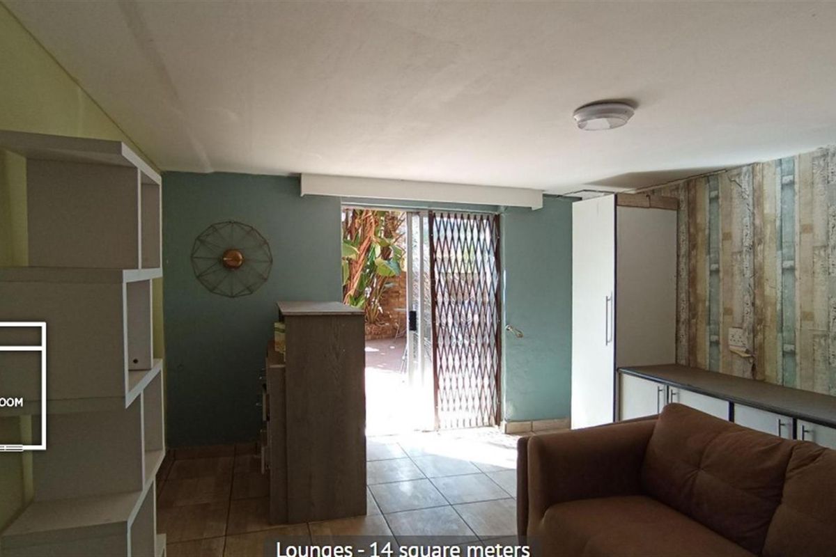 A living area featuring tiled flooring, built-in cabinetry, and a security gate leading to an outdoor space.