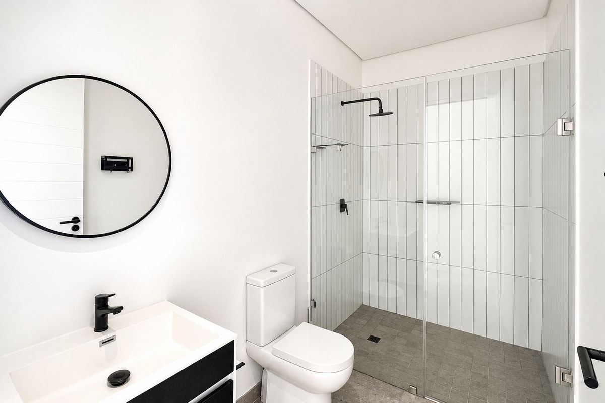 Modern bathroom featuring a walk-in shower with black matte fixtures, a sleek vanity with a ceramic basin, and contemporary vertical wall tiling.