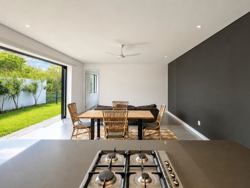 Modern open-plan living and dining area featuring a gas hob, recessed lighting, and large sliding doors opening to a private garden.