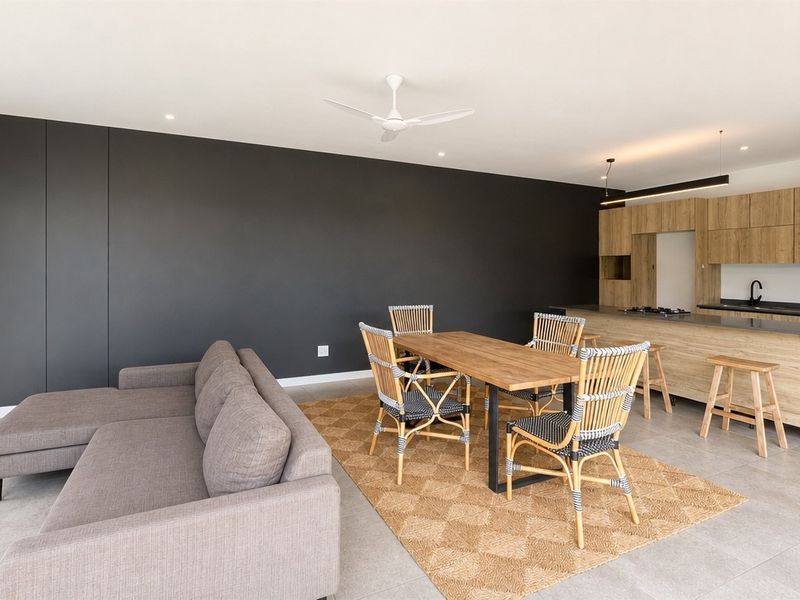 Modern open-plan living and dining area featuring a contemporary kitchen with wood-finish cabinetry, a central island, and sleek tiled flooring.