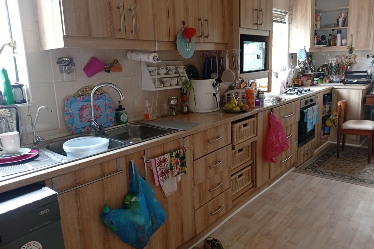 A functional kitchen featuring wood-look cabinetry, laminate countertops, a stainless steel double sink, and built-in oven with hob.