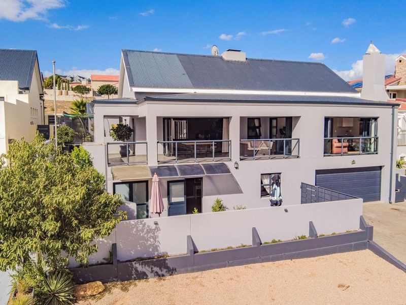 Aerial view of a modern two-story residential property featuring a spacious upper balcony, integrated garage, and a well-maintained exterior facade.