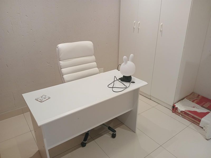 A functional office space featuring built-in cupboards and tiled flooring, providing a clean and practical area for work or study.