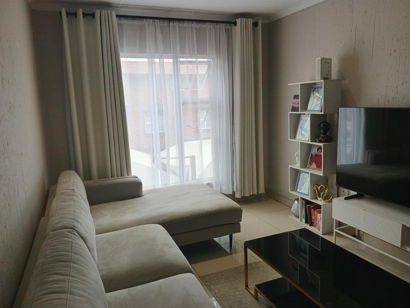 A well-maintained living room featuring neutral tiled flooring and a large sliding glass door that provides natural light.