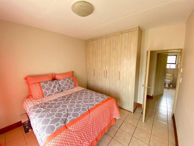 A bedroom featuring tiled flooring, a built-in wardrobe, and direct access to an en-suite bathroom.