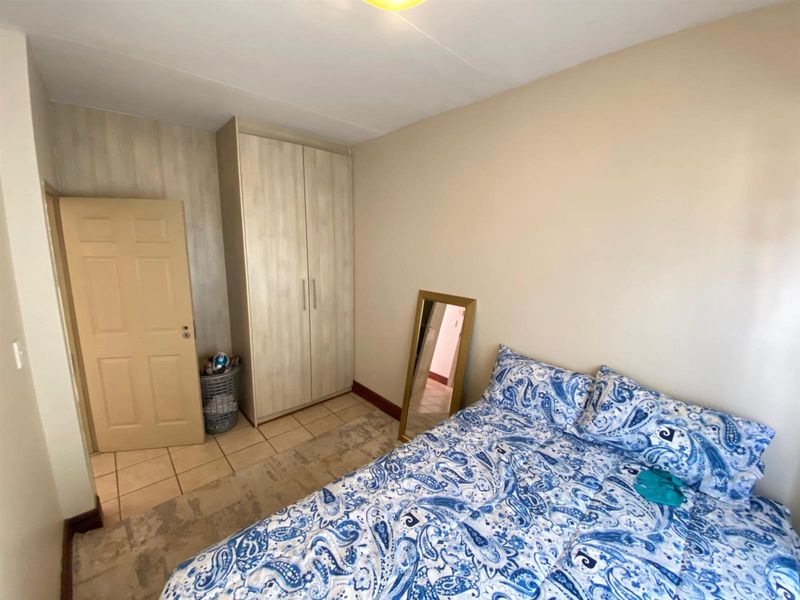 A functional bedroom featuring tiled flooring and a built-in wardrobe, offering a clean and neutral space ready for personalization.