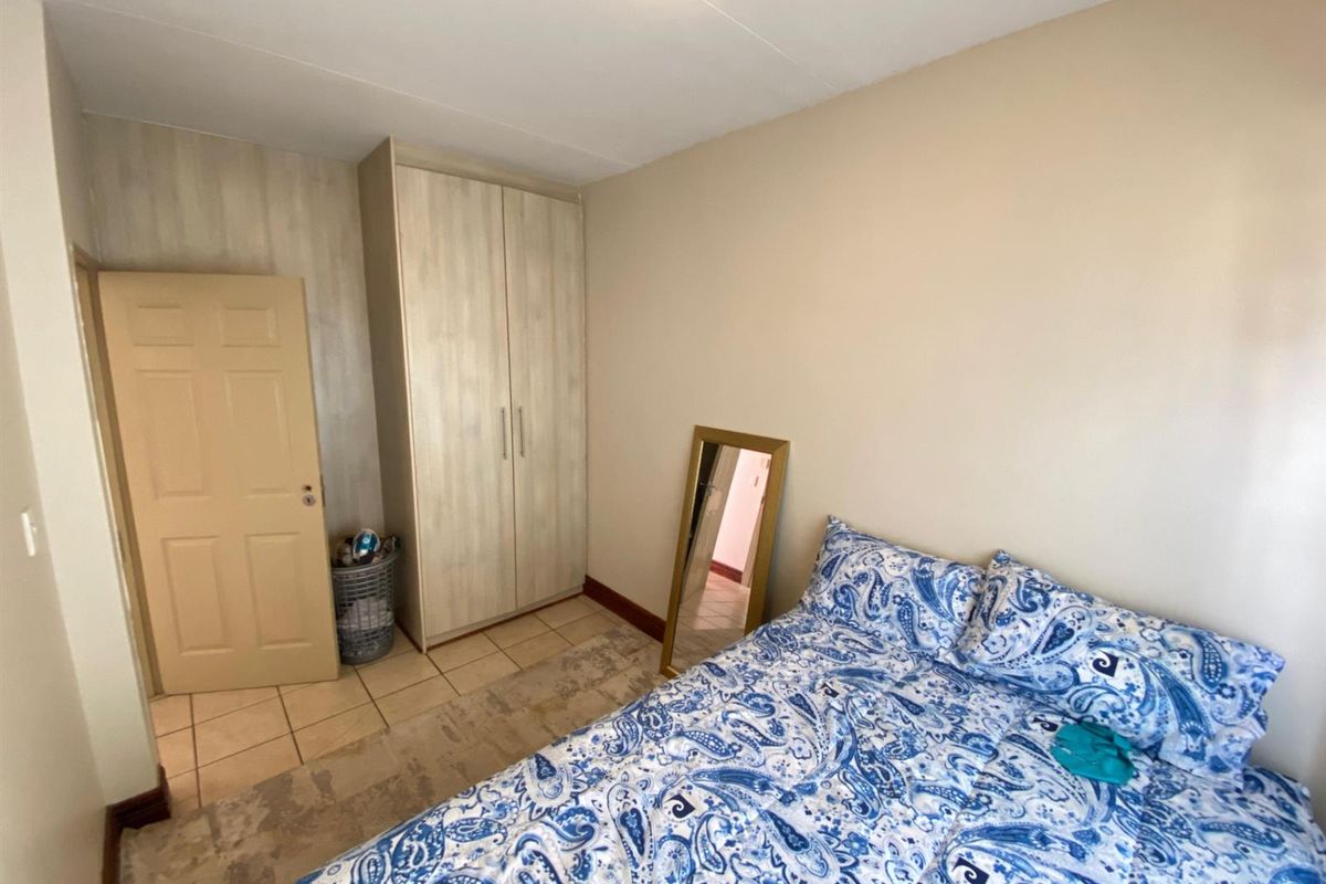 A functional bedroom featuring tiled flooring and a built-in wardrobe, offering a clean and neutral space ready for personalization.