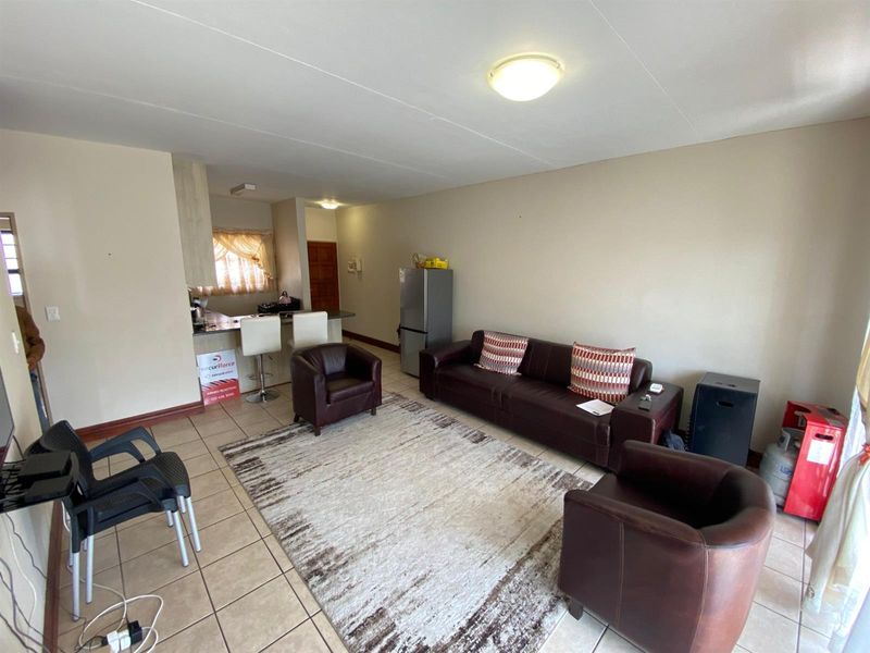 Open-plan living area featuring tiled flooring and a breakfast bar, creating a functional space that connects the kitchen and lounge.