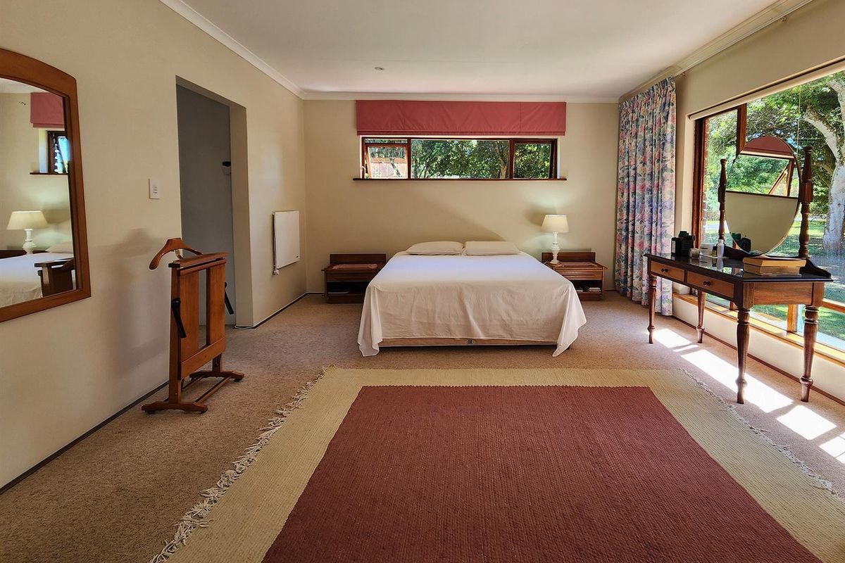 Spacious bedroom featuring large windows with garden views, neutral carpeting, and built-in wall heater.