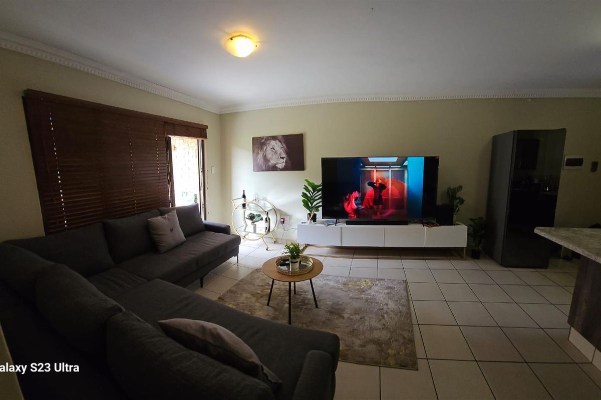 A comfortable living area featuring tiled flooring, crown molding, and wooden blinds, providing a functional space for relaxation.