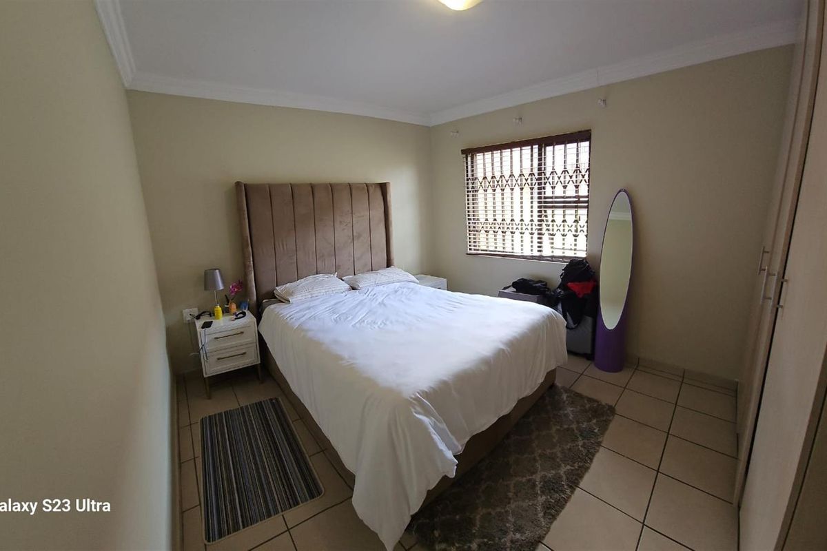 A bedroom featuring tiled flooring, built-in cupboards, and a window with fitted blinds.
