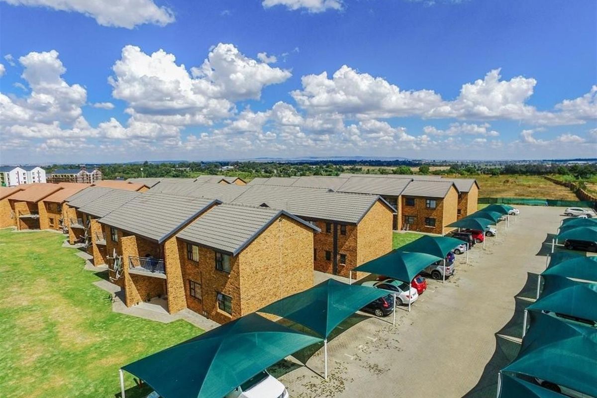 Aerial view of an apartment complex featuring brick facade buildings, tiled roofs, and designated shaded parking bays set within a landscaped residential estate.
