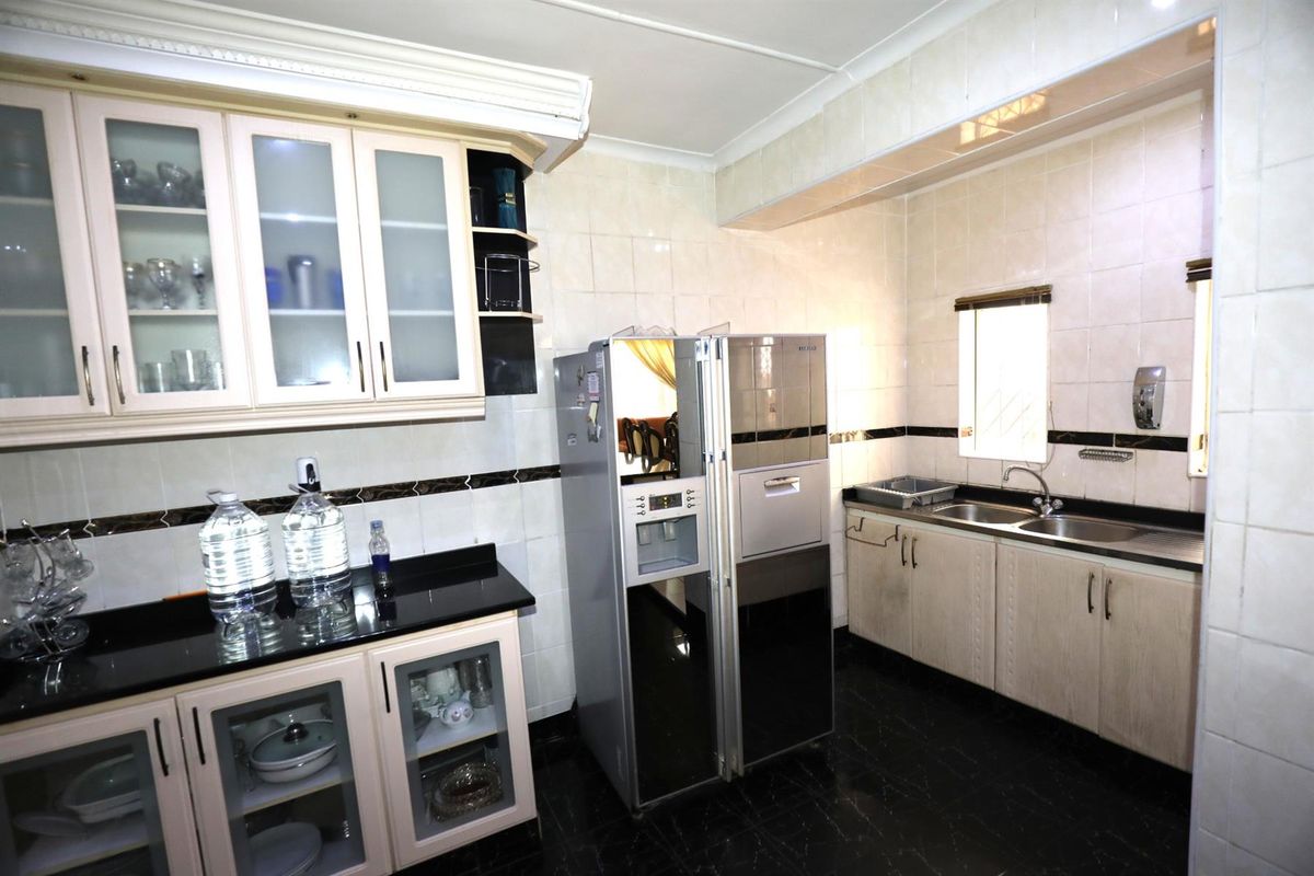 A functional kitchen featuring built-in cabinetry, granite countertops, double stainless steel sink, and tiled wall finishes.