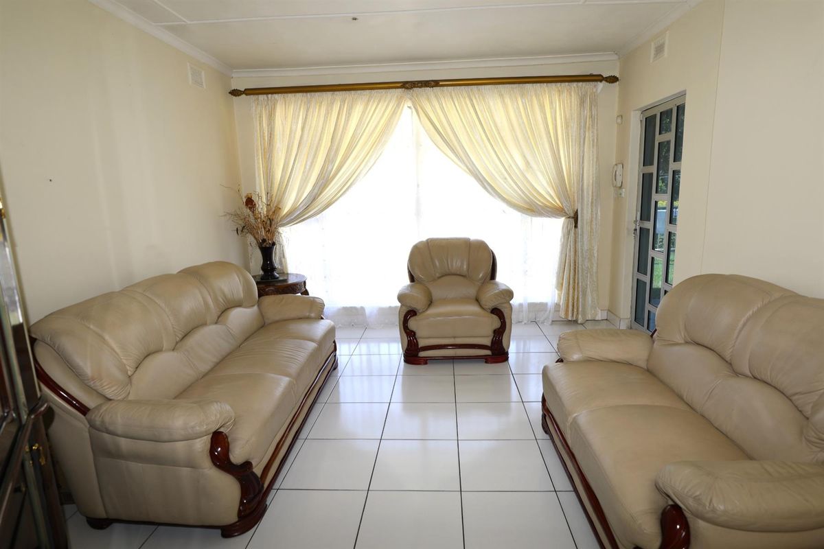 A bright living room featuring large windows with curtains and tiled flooring, providing a functional and well-lit space.