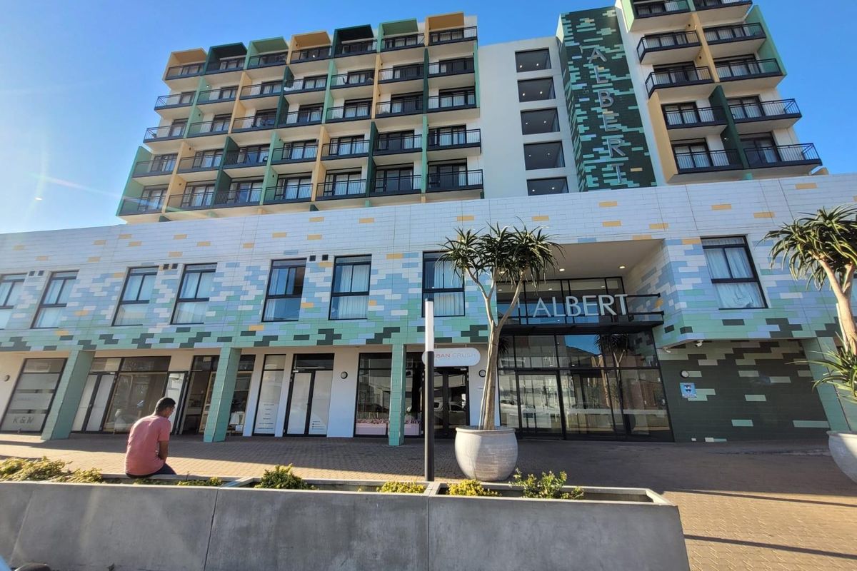 Modern multi-story apartment building facade featuring contemporary tiled cladding, private balconies, and a prominent glass-fronted entrance.