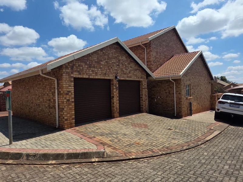 Front view of a brick-faced house featuring a double garage and a paved driveway in a residential estate setting.