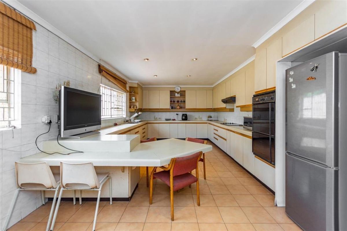Spacious kitchen featuring extensive built-in cabinetry, integrated oven, hob, and a breakfast bar area with tiled flooring.