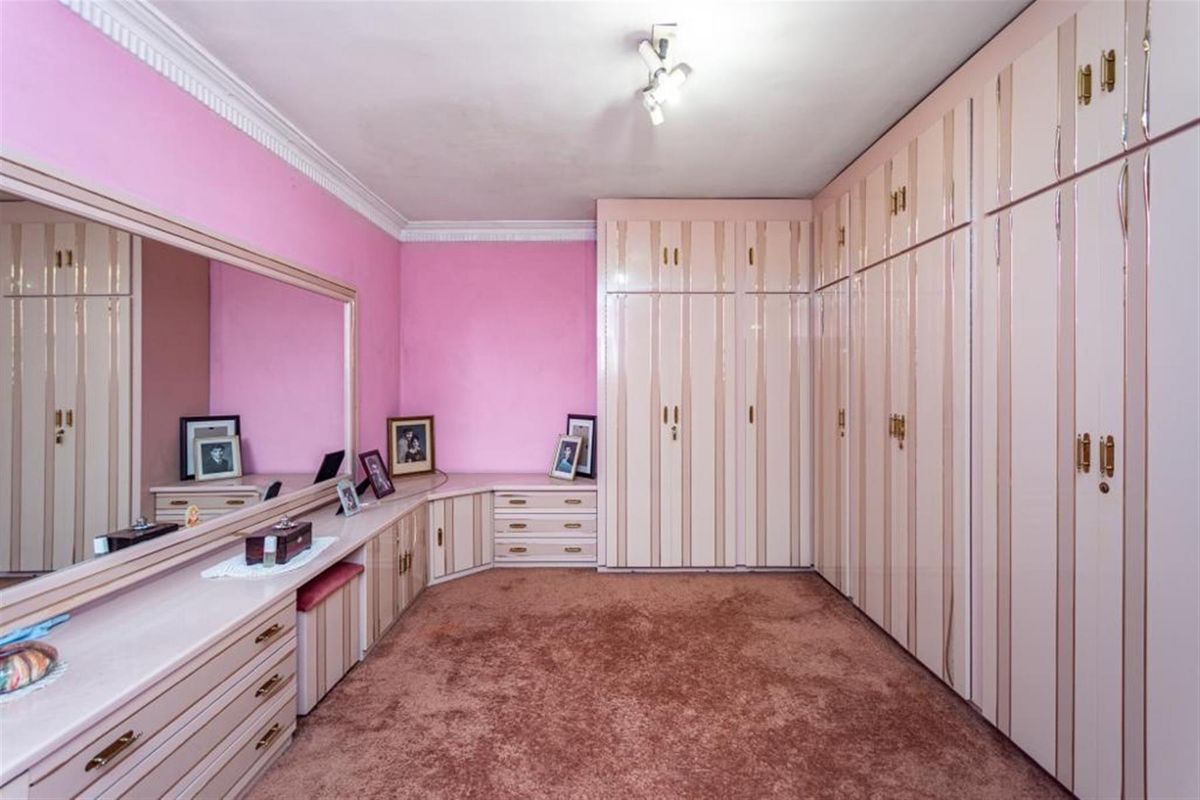 A bedroom featuring extensive built-in cabinetry, a large integrated vanity mirror, and wall-to-wall carpeting.