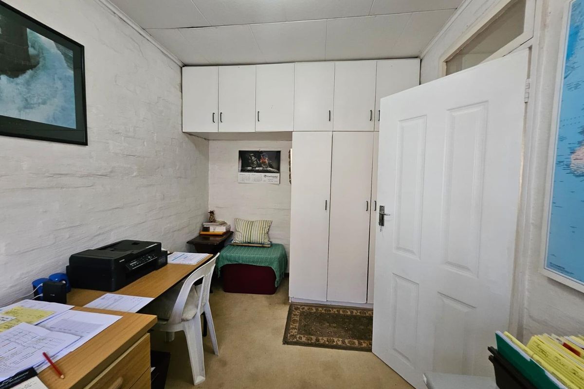 A functional bedroom featuring built-in cupboards with overhead storage, painted brick walls, and carpeted flooring.
