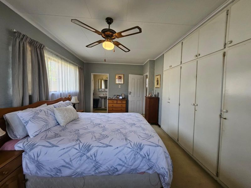 Spacious bedroom featuring extensive built-in cupboards, a ceiling fan, and direct access to an en-suite bathroom.