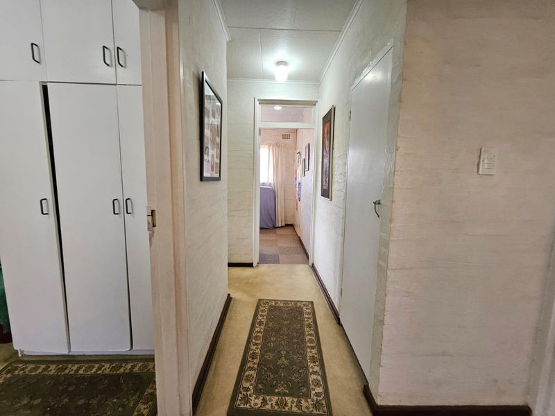 A functional hallway featuring built-in storage cupboards, painted brick walls, and access to adjacent rooms.