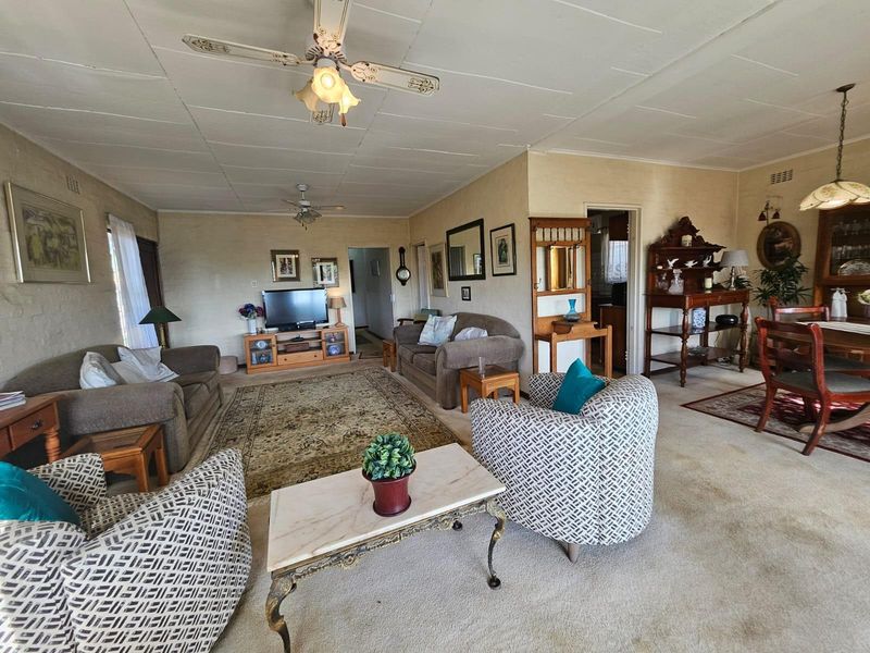 Spacious open-plan living and dining area featuring carpeted flooring, ceiling fans, and a neutral color palette, offering a versatile layout for family living.