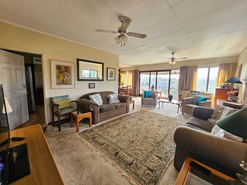 Spacious living room featuring ceiling fans, carpeted flooring, and large sliding glass doors that provide natural light and access to the outdoor area.