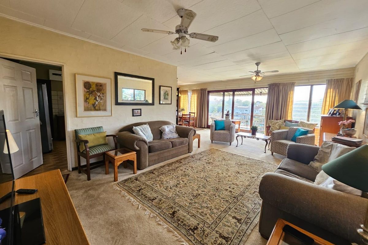 Spacious living room featuring ceiling fans, carpeted flooring, and large sliding glass doors that provide natural light and access to the outdoor area.